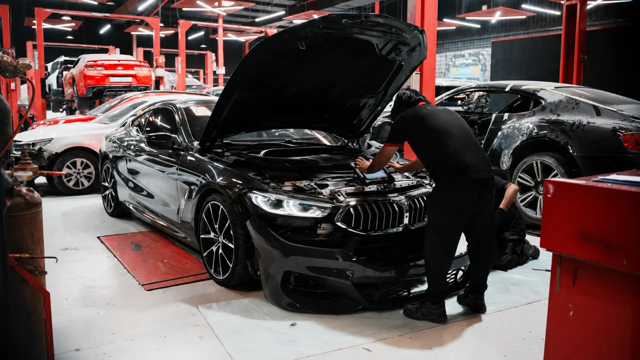 A technician working under the bonnet of a BMW in the bay at Al Zaabi Autocare, Mussafah