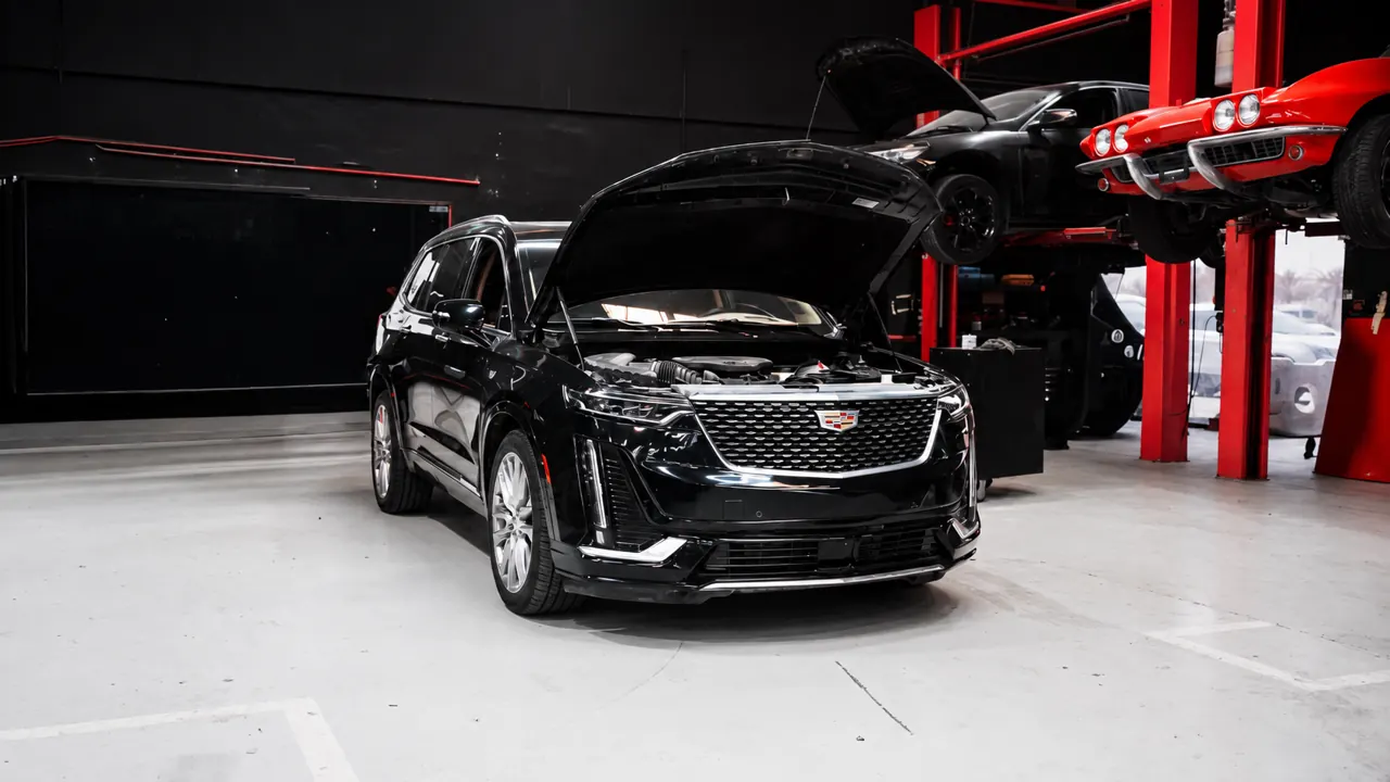 A Cadillac XT6 with the bonnet up in the bay at Al Zaabi Autocare, Mussafah