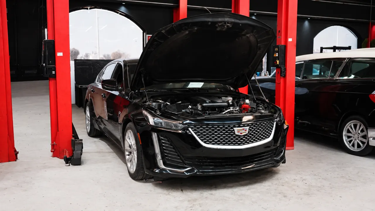 A Cadillac CT5 between the lifts in the bay at Al Zaabi Autocare, Mussafah