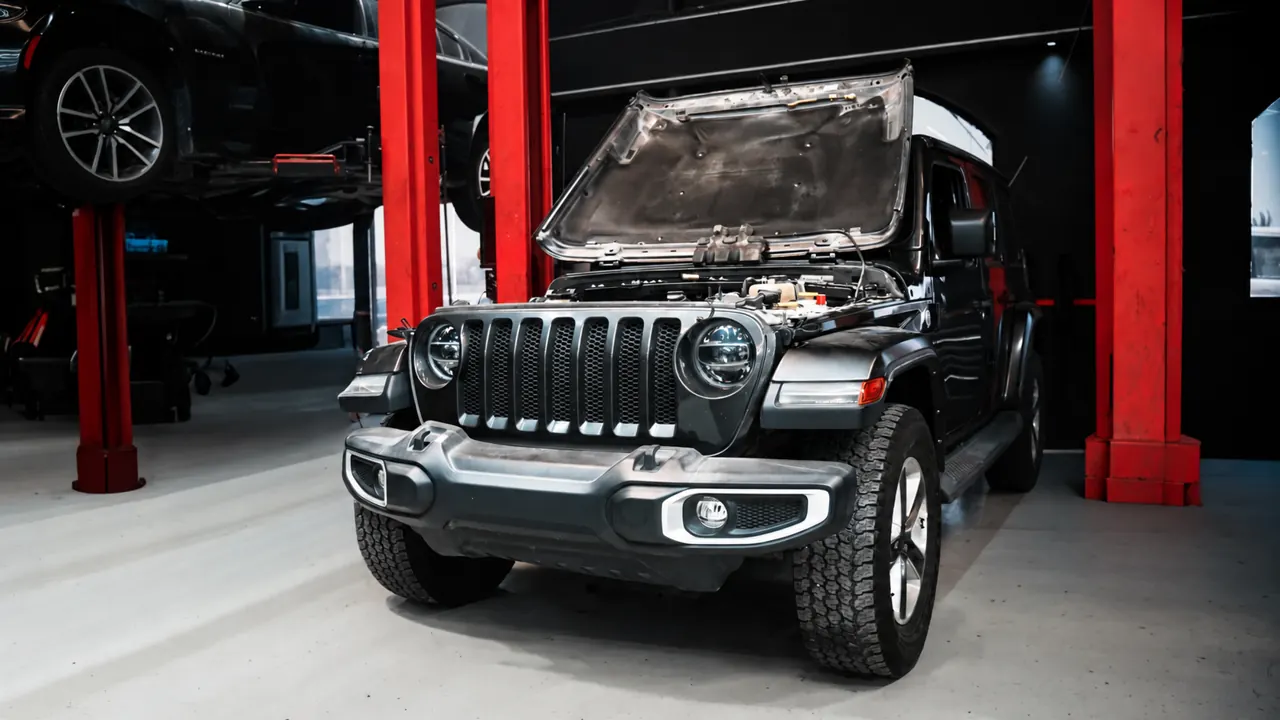 A Jeep Wrangler with the bonnet up in the bay at Al Zaabi Autocare, Mussafah
