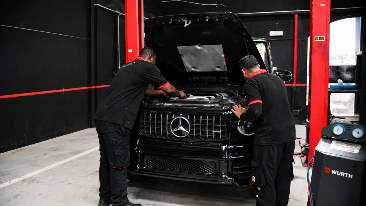 Two technicians working on a Mercedes G-Class in the bay at Al Zaabi Autocare, Mussafah
