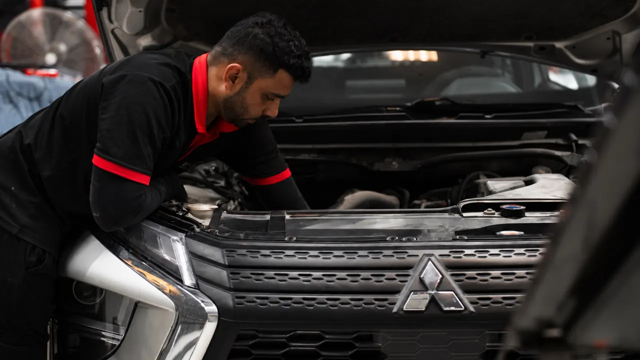 A technician working under the bonnet of a Mitsubishi in the bay at Al Zaabi Autocare, Mussafah