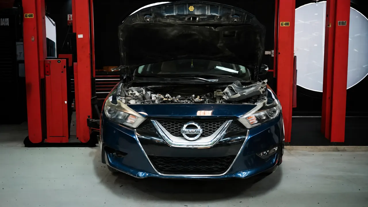 A Nissan Maxima with the bonnet up in the bay at Al Zaabi Autocare, Mussafah